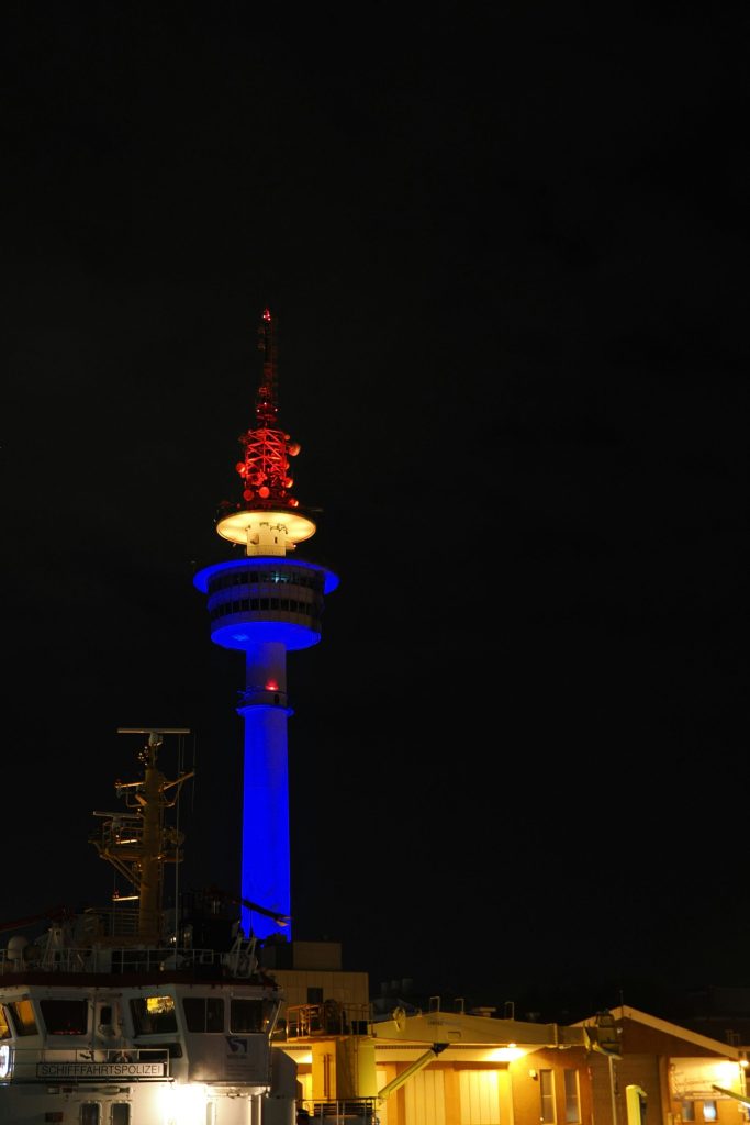 Tall tower illuminated with blue and red lights at night.